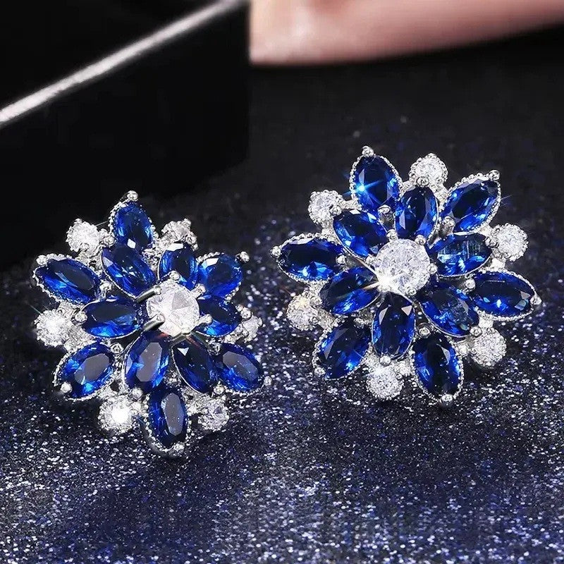 Pair of blue and silver floral earrings on a dark background