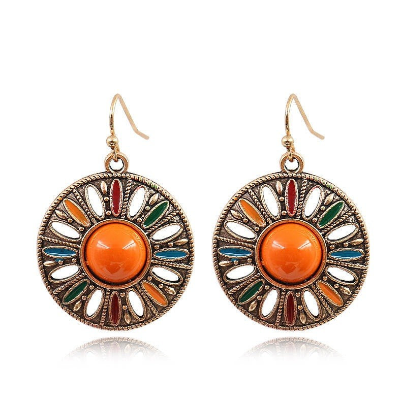 A pair of bohemian-style round drop earrings with antique bronze filigree detailing, featuring a central orange cabochon and colorful enamel accents in red, green, and blue.