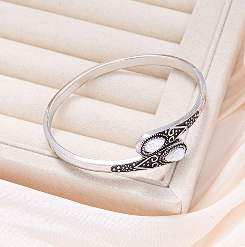 Silver bracelet with intricate design on a soft beige background