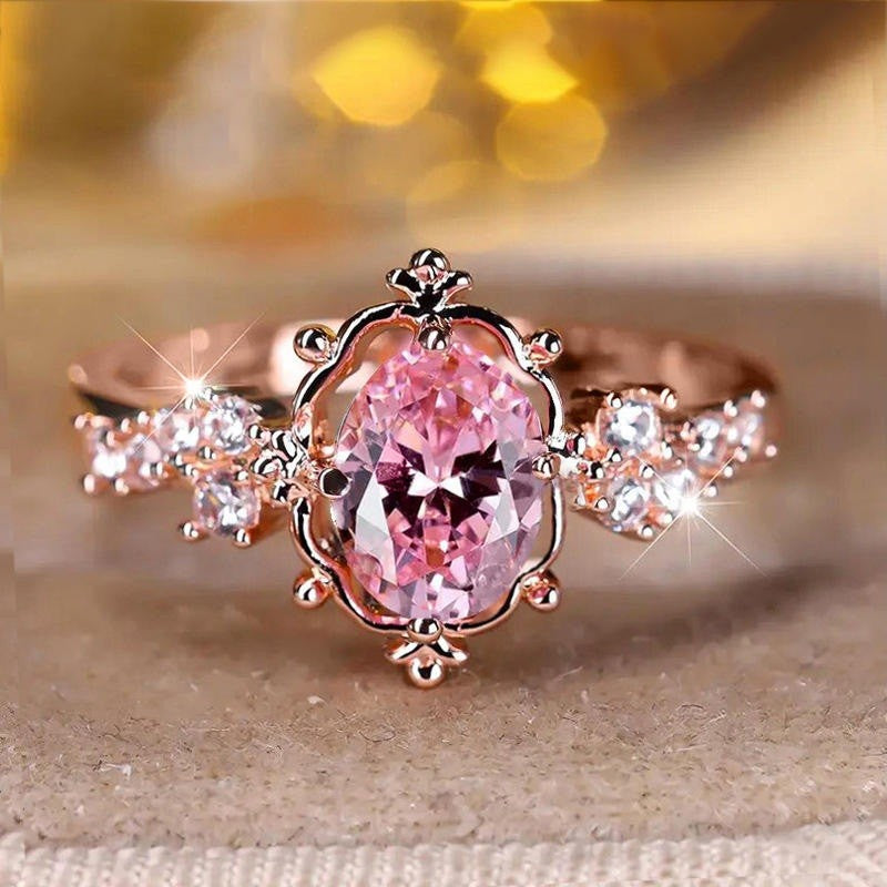 Rose gold ring with a pink gemstone on a beige surface