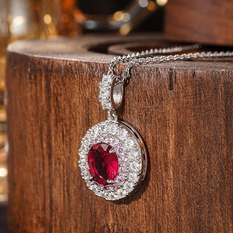 Silver pendant with a red gemstone on a wooden surface