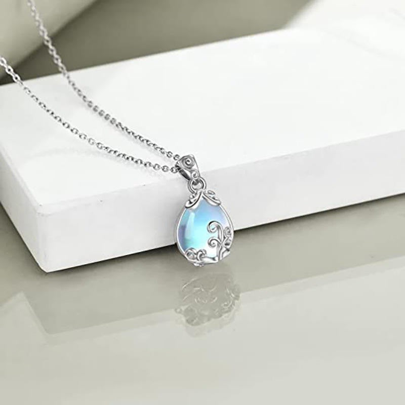 Teardrop-shaped pendant with a blue opal-like stone on a white surface