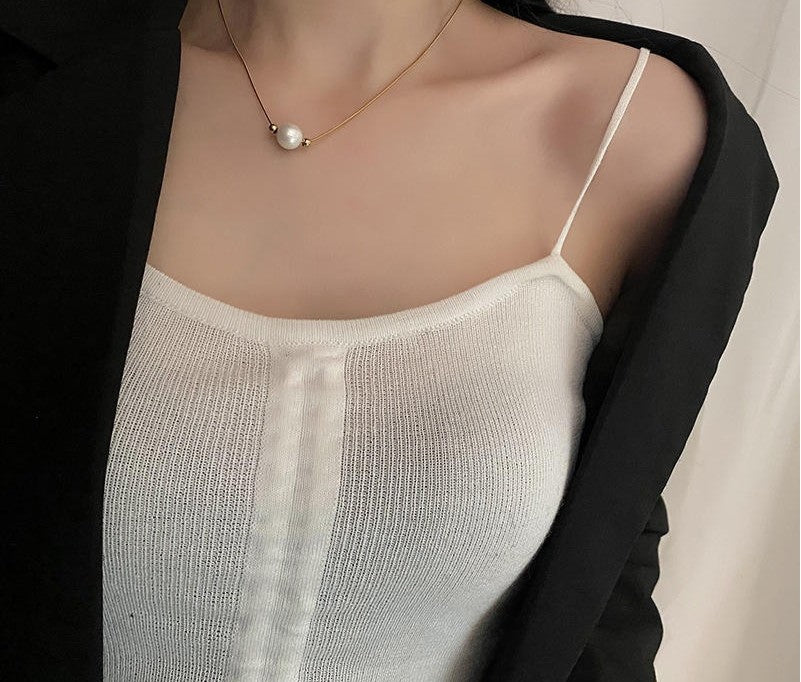 Person wearing a pearl necklace with a plain background