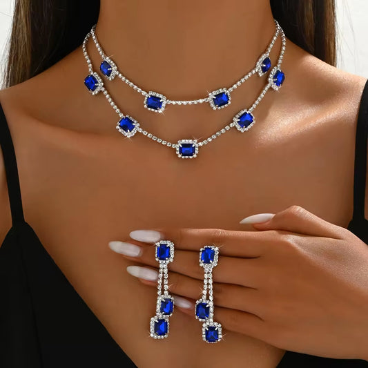 Jewelry set with necklace and earrings featuring blue gemstones on a model.