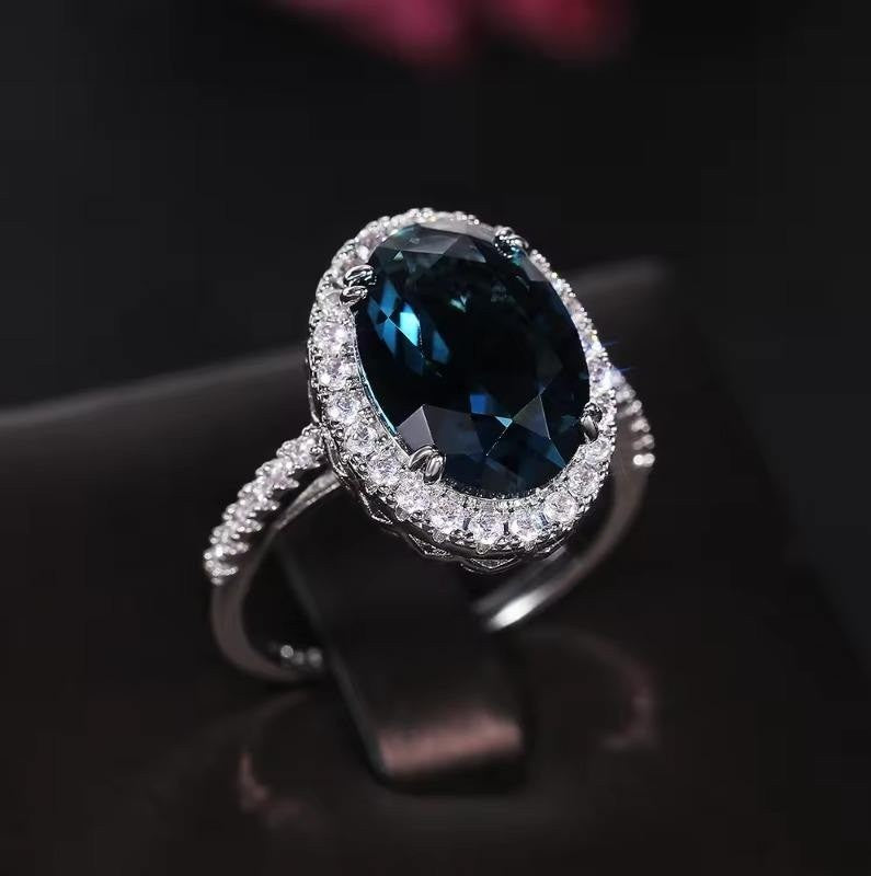 Ring with a blue gemstone and diamond-studded band on a dark background