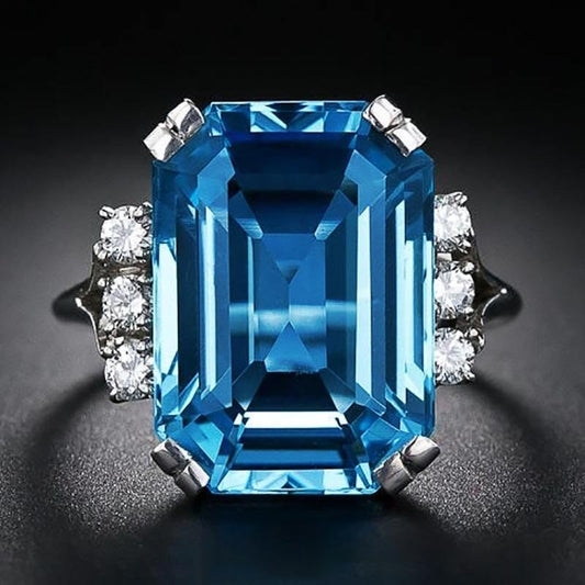 Ring with a large blue gemstone and smaller diamonds on a dark background
