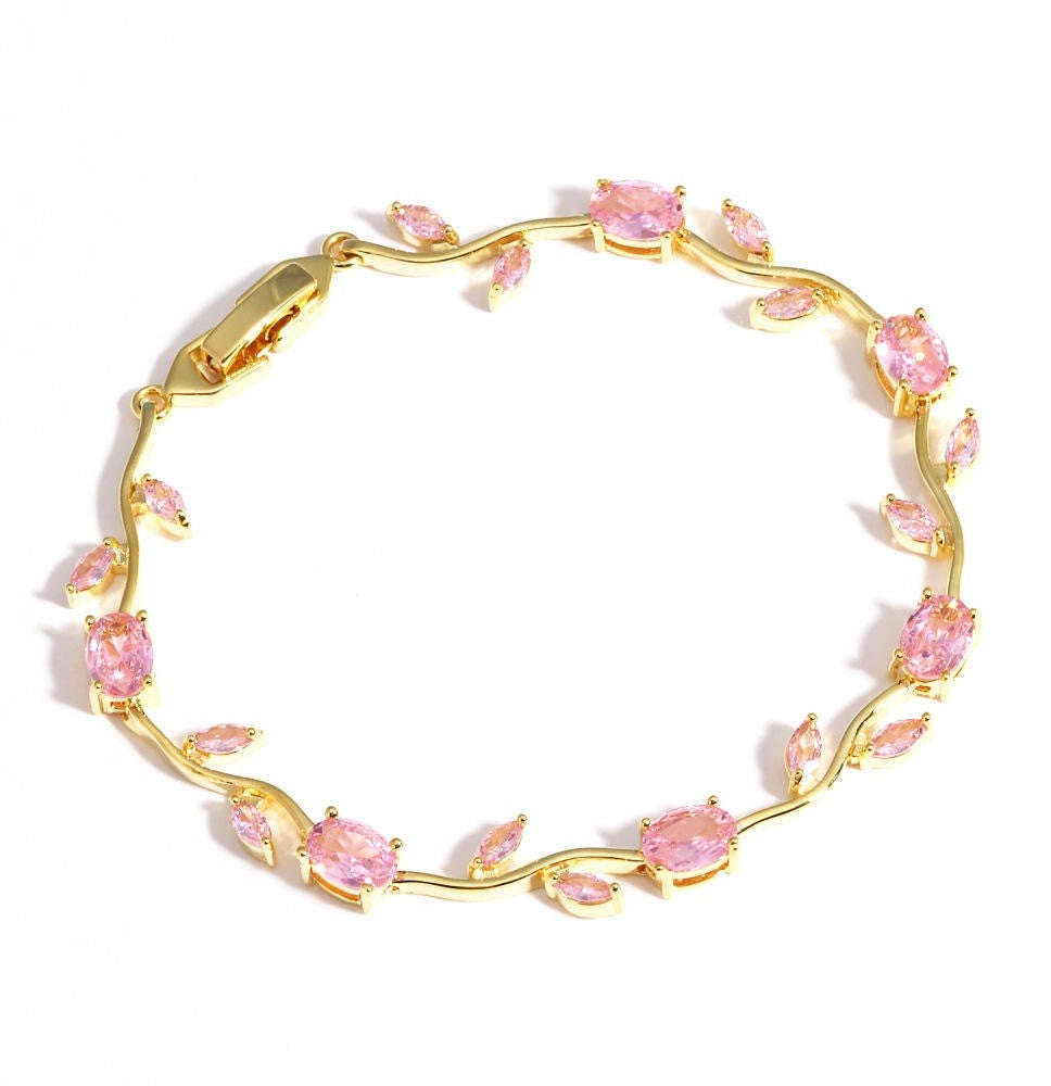 A gold leaf vine bracelet adorned with marquise-cut pink gemstones, displayed on a clean white background.