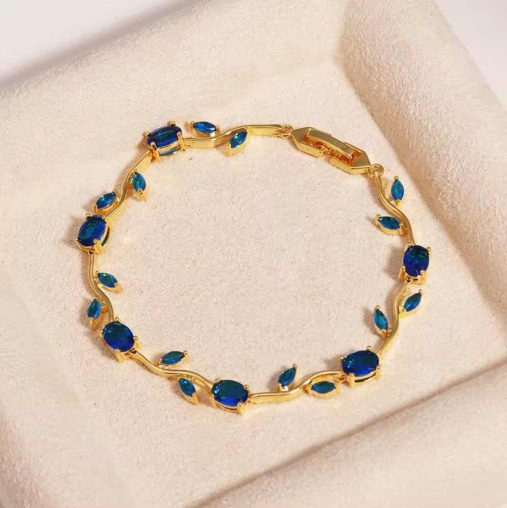 Gold bracelet with blue stones on a beige surface