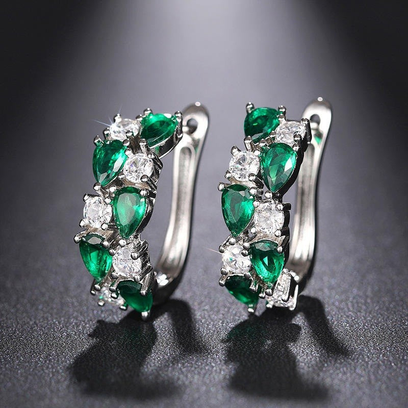Pair of emerald and diamond earrings on a dark background