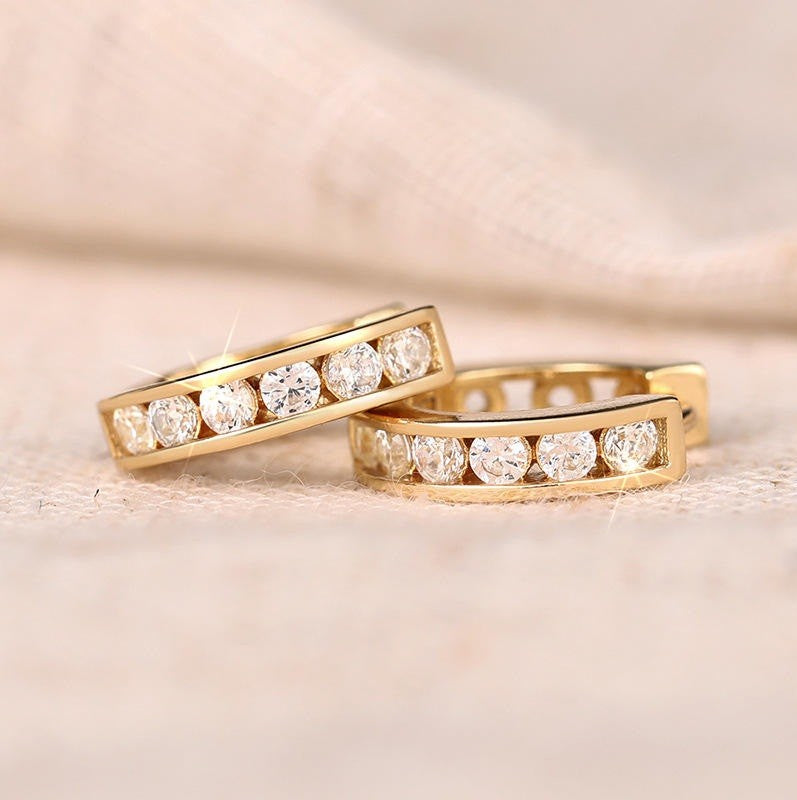 a pair of gold earrings with diamond like gemstones