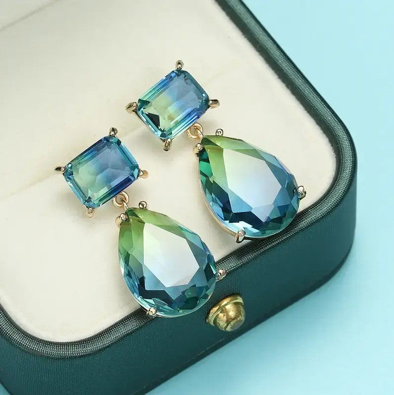 blue and gold earrings displayed on a cream box