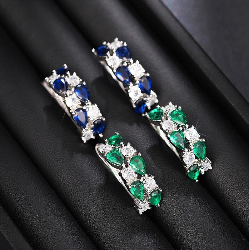 Pair of earrings with blue and green gemstones on a black background