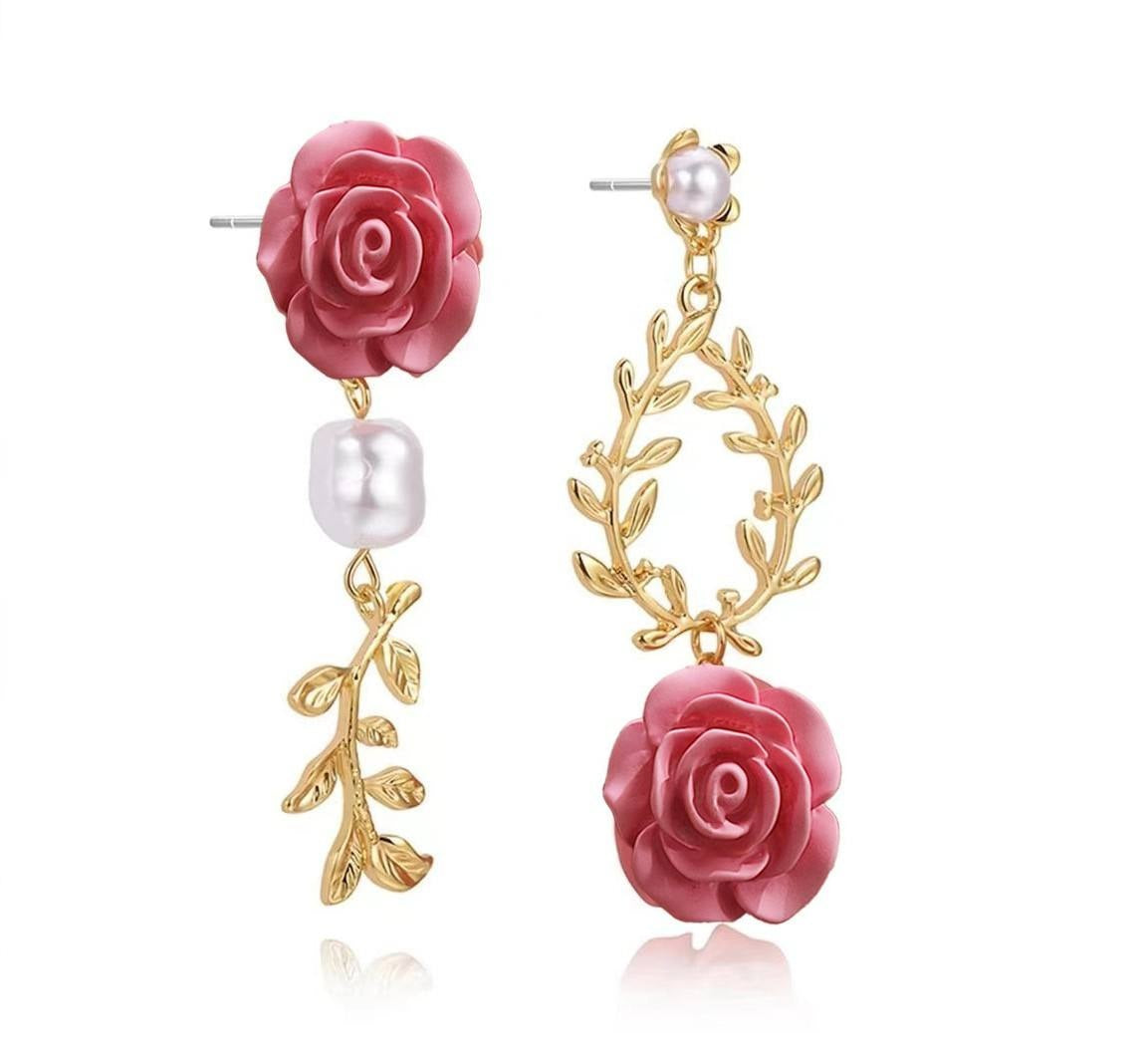 A pair of gold and pink drop earrings featuring 3D rose and leaf motifs, with a white pearl accent, shown on a clean white background.