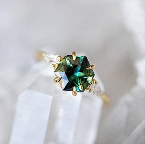 Gold ring with a green gemstone on a white background