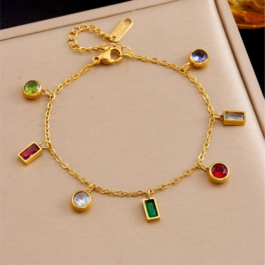 Gold bracelet with colorful gemstones on a beige surface