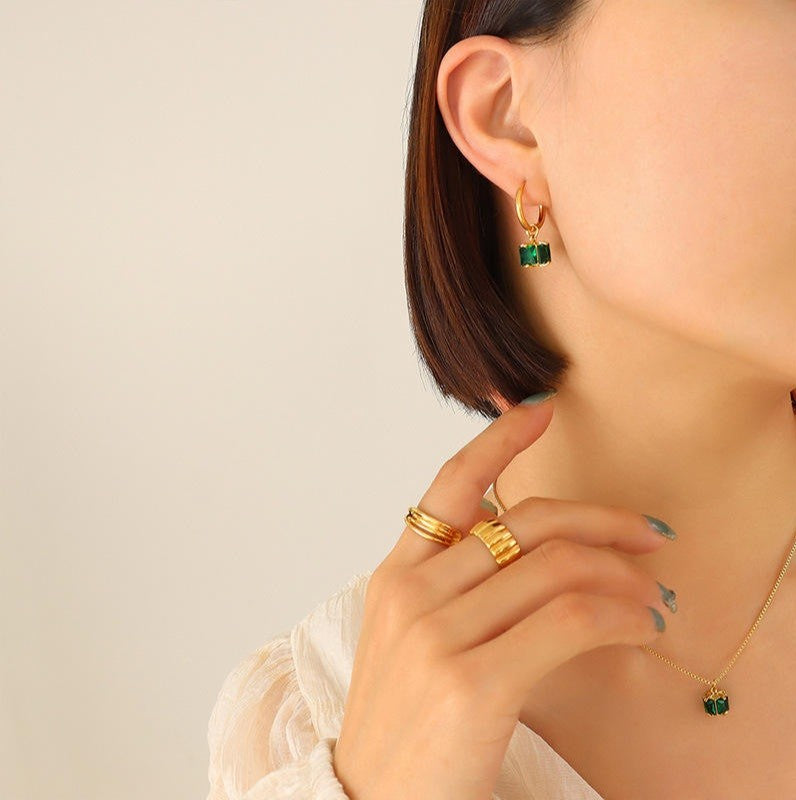Gold earrings and rings on a neutral background