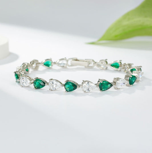 Silver bracelet with green and clear gemstones on a white background