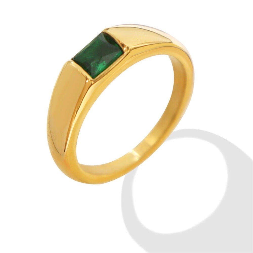Gold ring with a green gemstone on a white background