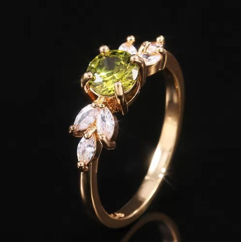 Gold ring with a green gemstone and diamond accents on a black background