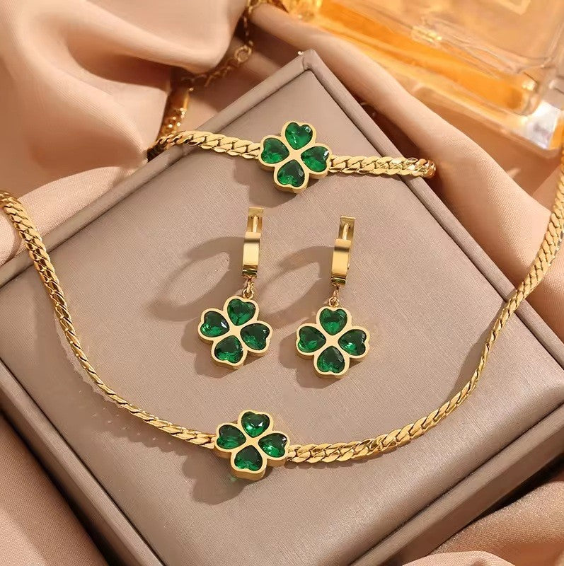 Gold jewelry set with green gemstones on a beige surface