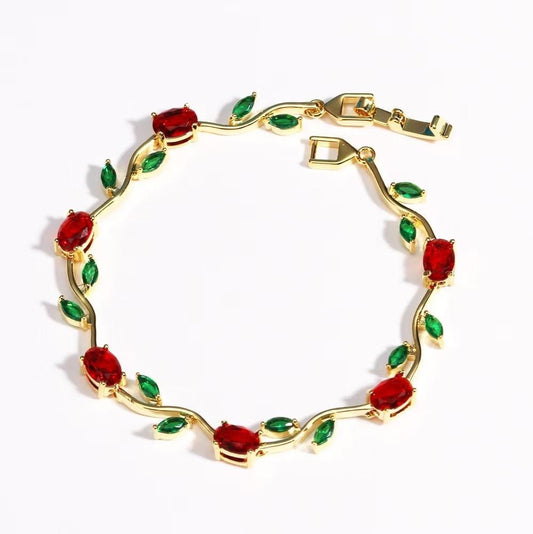 Gold bracelet with red and green gemstones on a white background