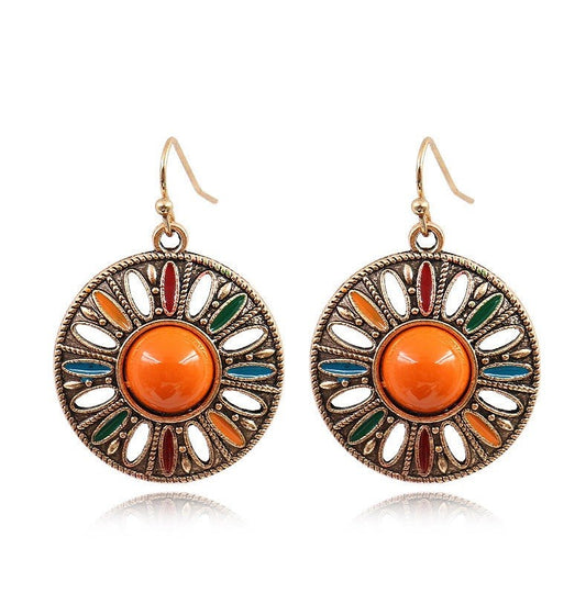A pair of bohemian-style round drop earrings with antique bronze filigree detailing, featuring a central orange cabochon and colorful enamel accents in red, green, and blue.
