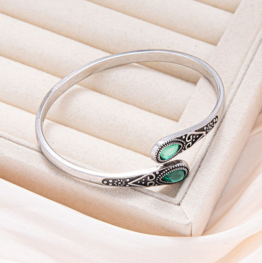 Silver bracelet with green gemstones on a soft beige background