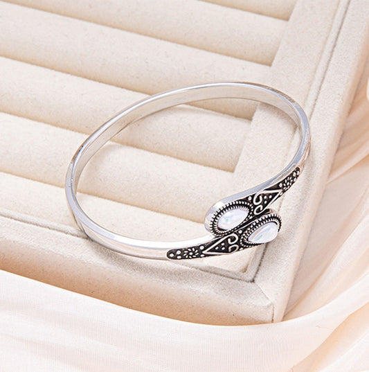 Silver bracelet with intricate design on a soft beige background