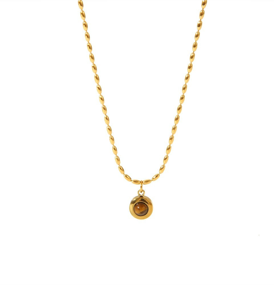 A gold chain necklace with a small round gold pendant featuring a brown gemstone, shown against a plain white background.