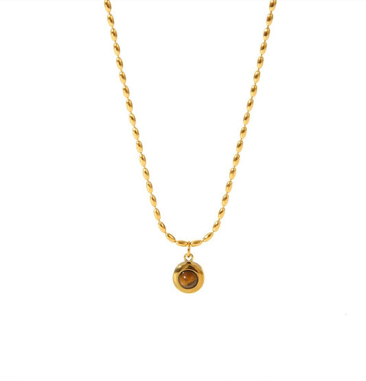 A gold chain necklace with a small round gold pendant featuring a brown gemstone, shown against a plain white background.