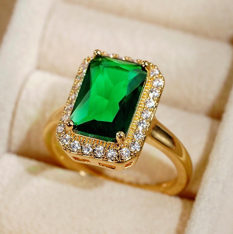 A yellow gold ring featuring a rectangular emerald-cut green gemstone