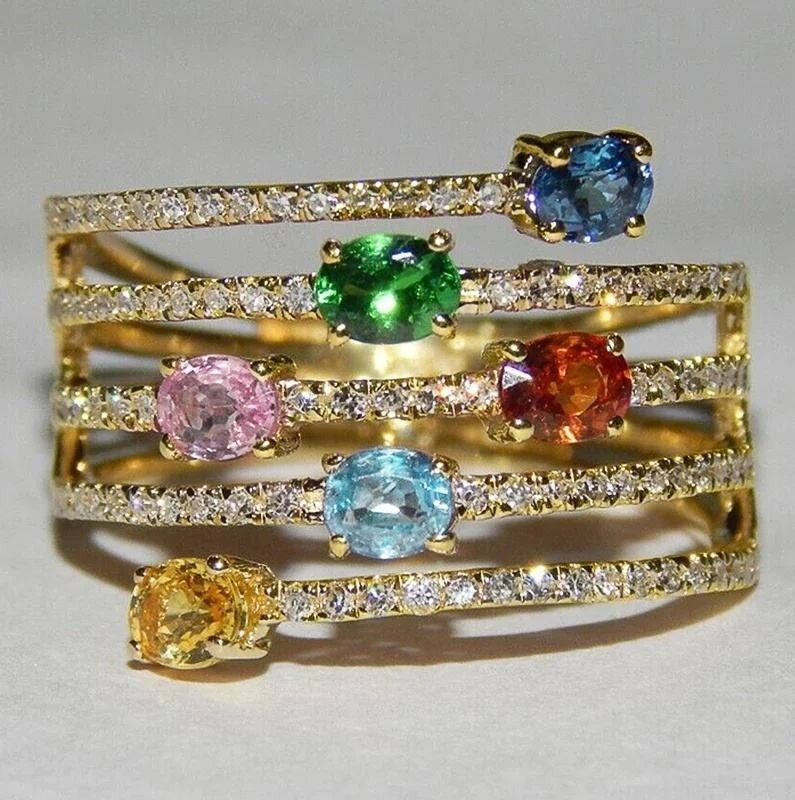 a gold ring with multi coloured gemstones on a grey background