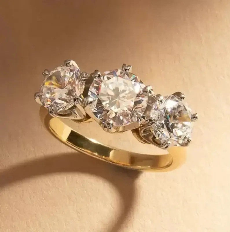 Gold ring with three large diamonds on a beige background