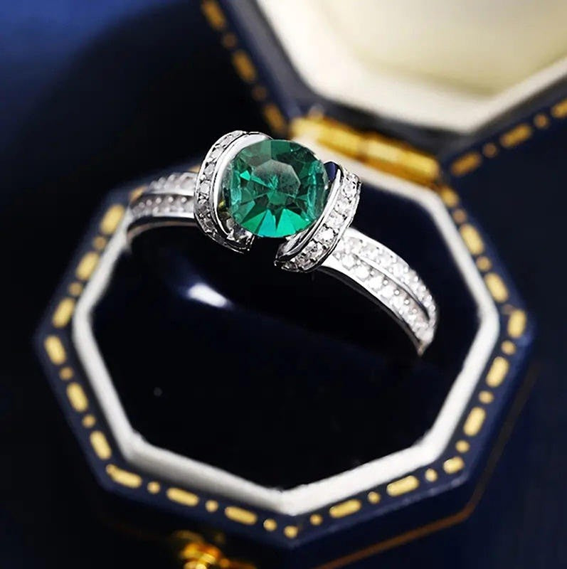 Ring with a green gemstone and diamond accents on a dark background