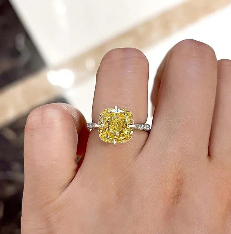 Yellow diamond ring on a finger with a blurred background