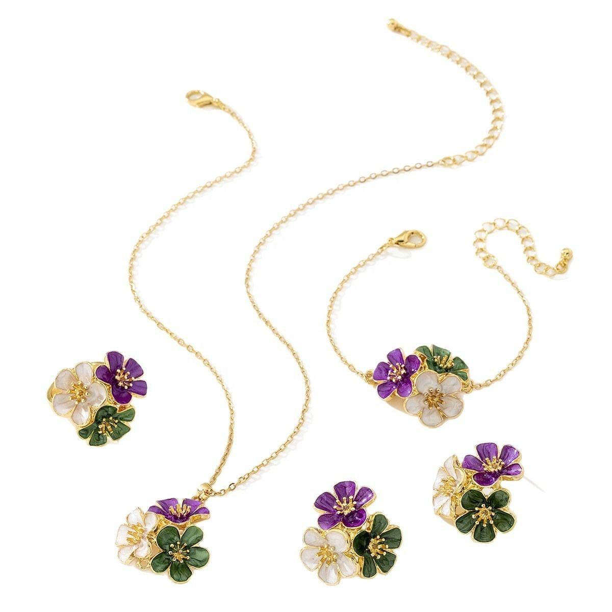 A gold-tone jewelry set featuring a necklace, bracelet, and matching earrings, each adorned with a flower charm in white, purple, and green enamel.