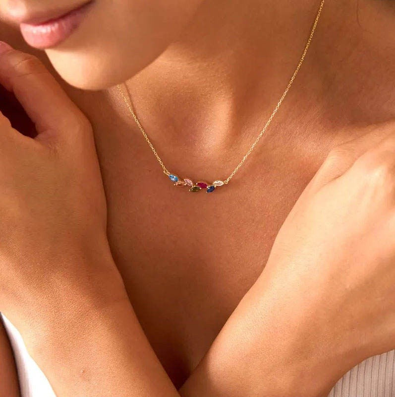 Gold necklace with colorful gemstones worn by a person