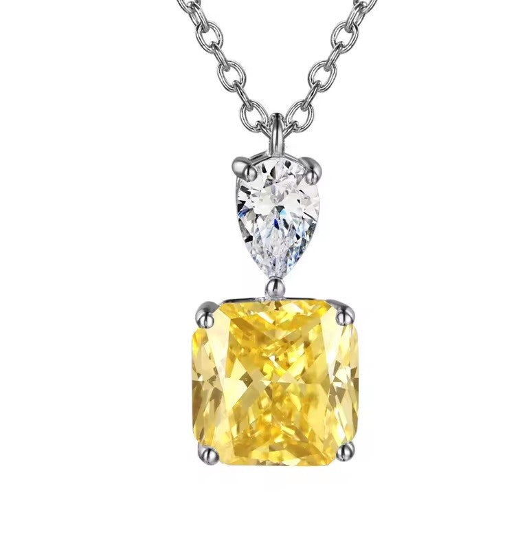 A yellow cushion-cut diamond pendant necklace with a silver-toned setting and a pear-cut clear diamond above it, suspended from a silver-toned chain against a white background.