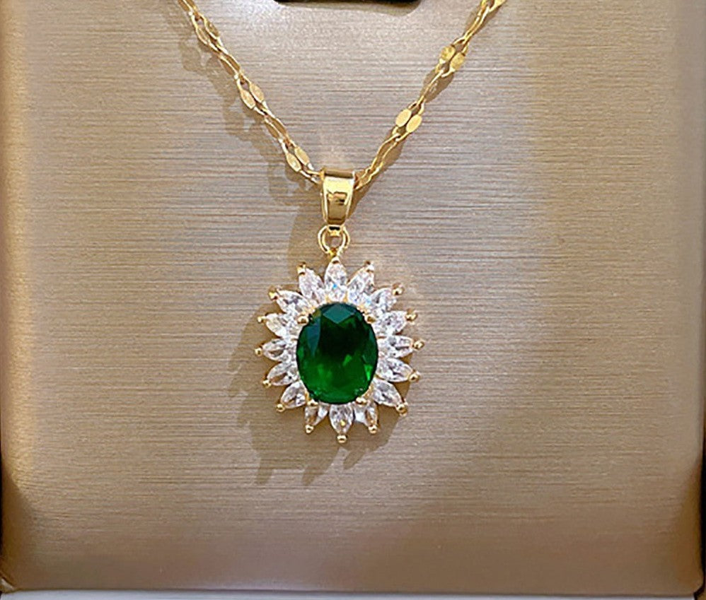 A gold pendant necklace featuring a central oval green gemstone surrounded by a halo of small clear stones, displayed on a textured beige jewelry box.