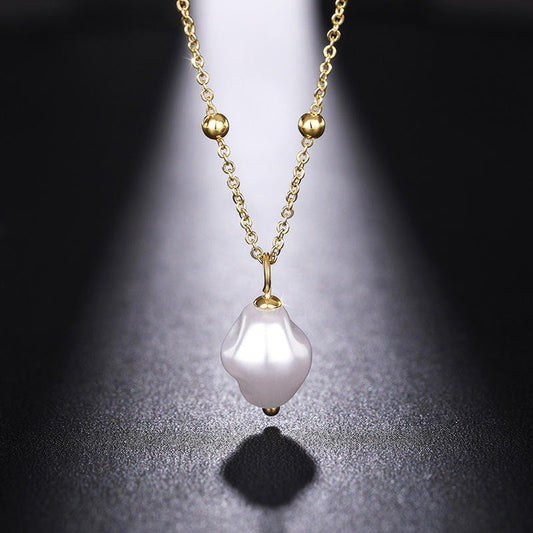 Gold necklace with a white pearl pendant on a dark background