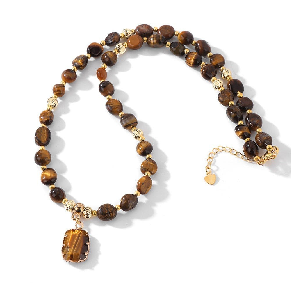 A beaded necklace featuring round brown tiger's eye beads and polished gold spacer beads, with a rectangular gold pendant showcasing a tiger's eye inlay. The necklace is displayed on a clean white background with soft shadows.