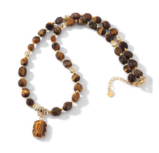 A beaded necklace featuring round brown tiger's eye beads and polished gold spacer beads, with a rectangular gold pendant showcasing a tiger's eye inlay. The necklace is displayed on a clean white background with soft shadows.