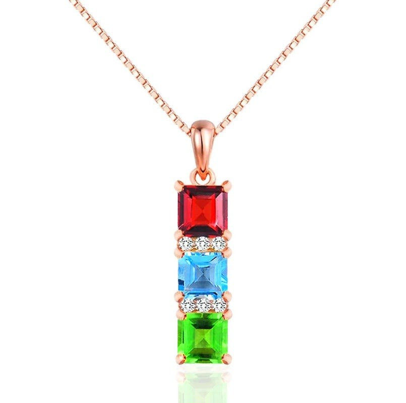 A rose gold necklace with a vertical rectangular pendant featuring four colored gemstone sections in red, light blue, clear rhinestones, and green, shown on a white background.