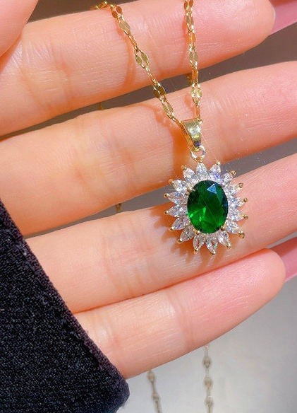 A gold pendant necklace featuring a central oval green gemstone