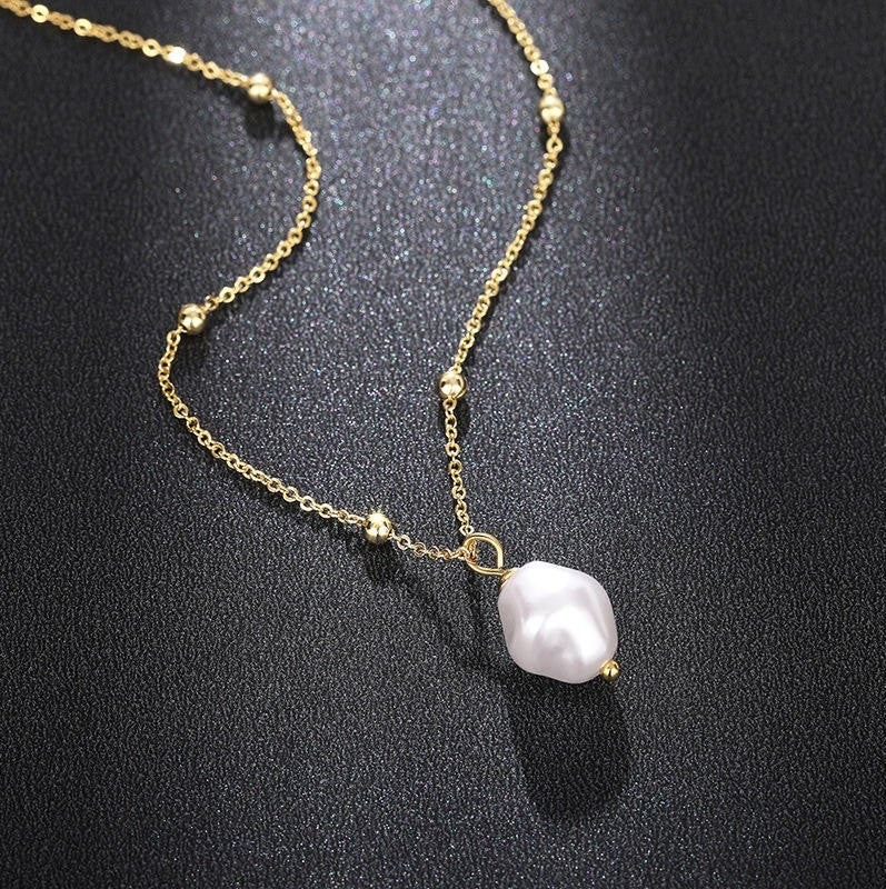 Gold necklace with a pearl pendant on a black background