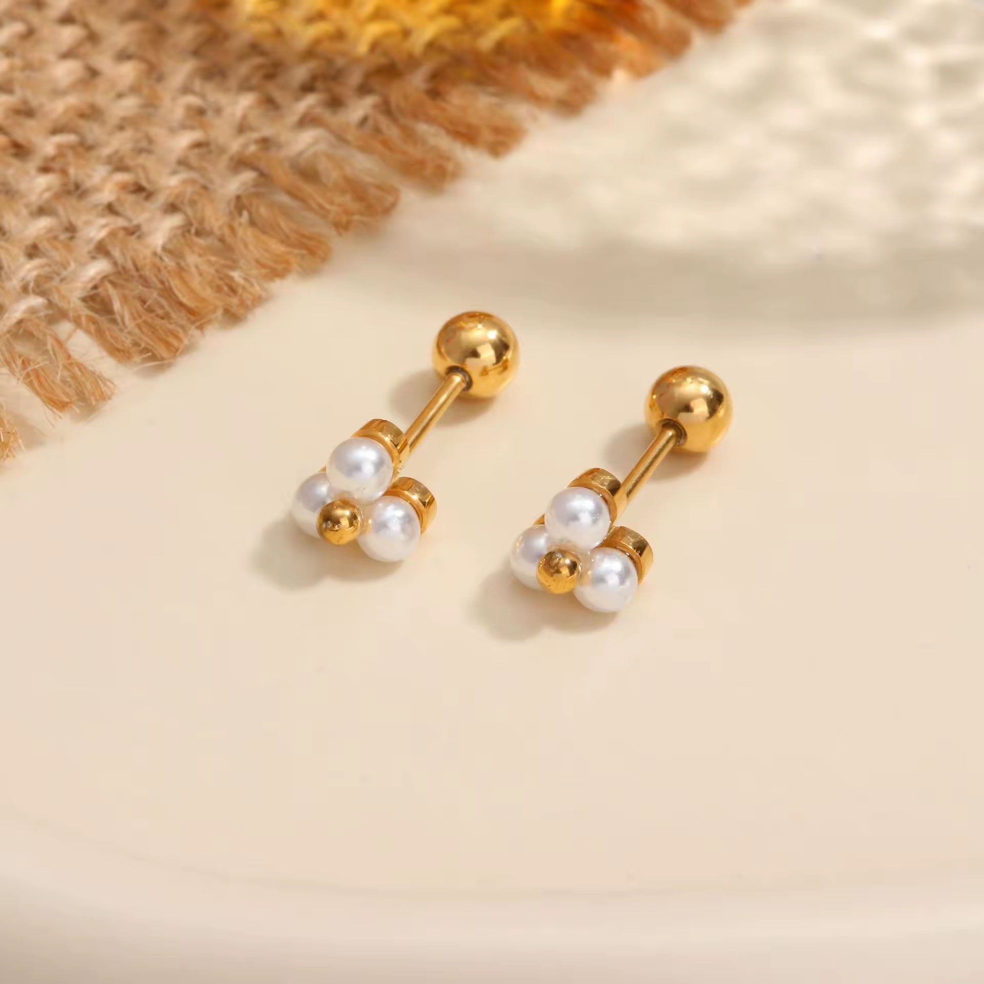 Gold earrings with pearl drops on a beige background