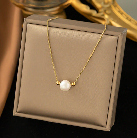 Gold necklace with a pearl pendant on a beige jewelry box