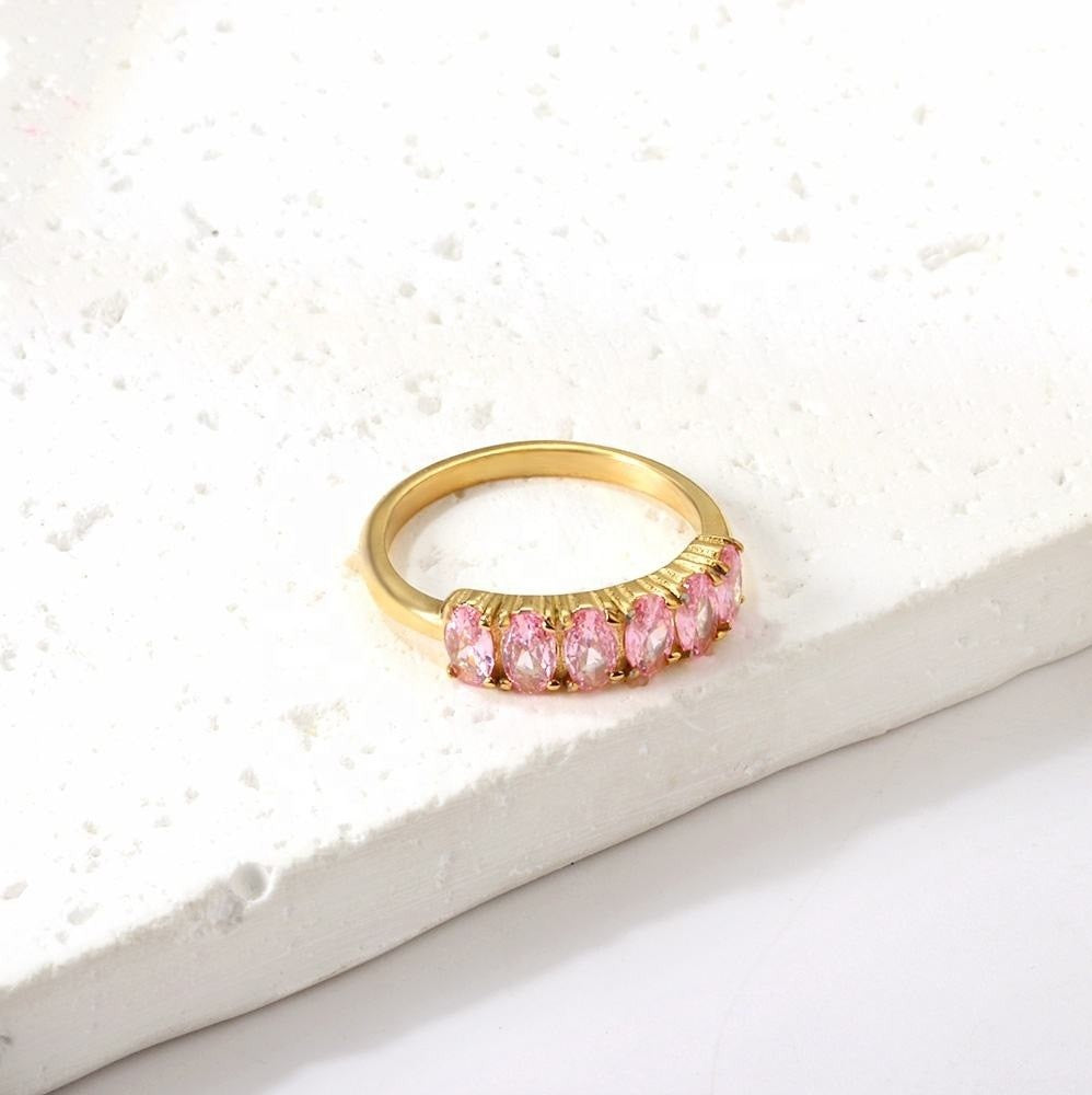 Gold ring with pink gemstones on a textured white surface