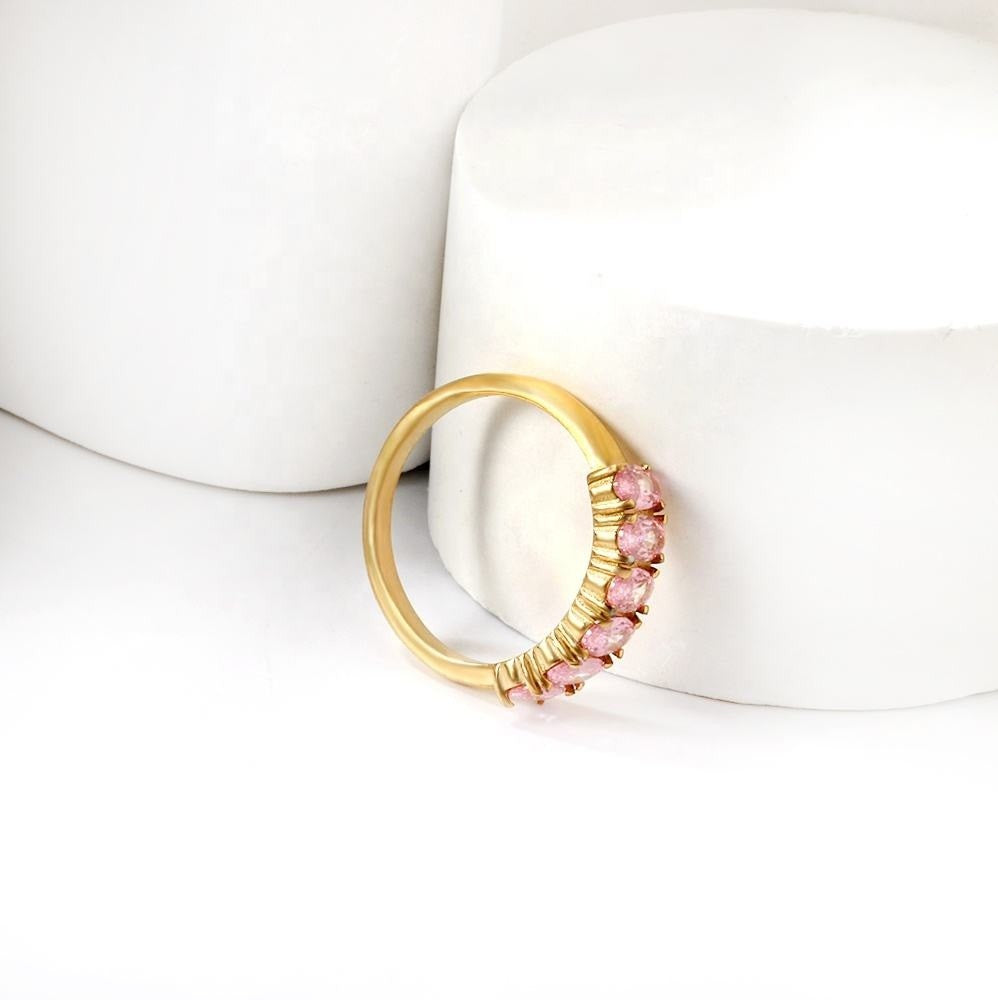 Gold ring with pink gemstones on a white surface