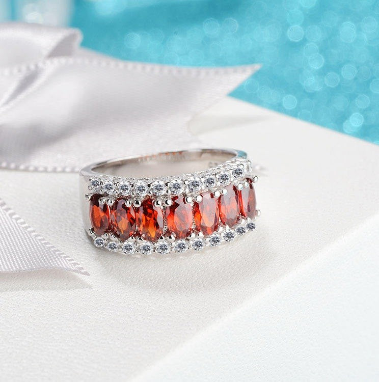 Silver ring with red gemstones on a white fabric background